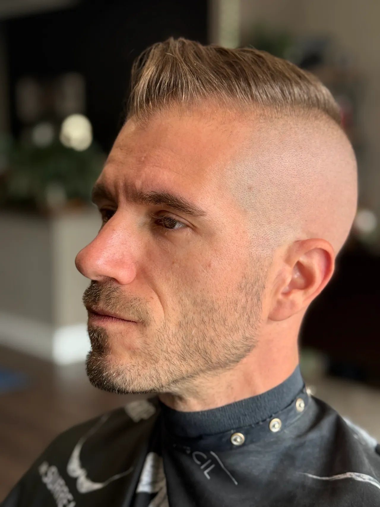 Man with spiked blonde hair and goatee in side profile wearing black shirt